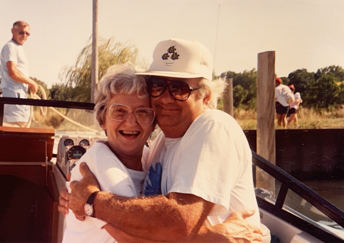 A vintage photograph of a couple embracing aboard a boat at the harbor